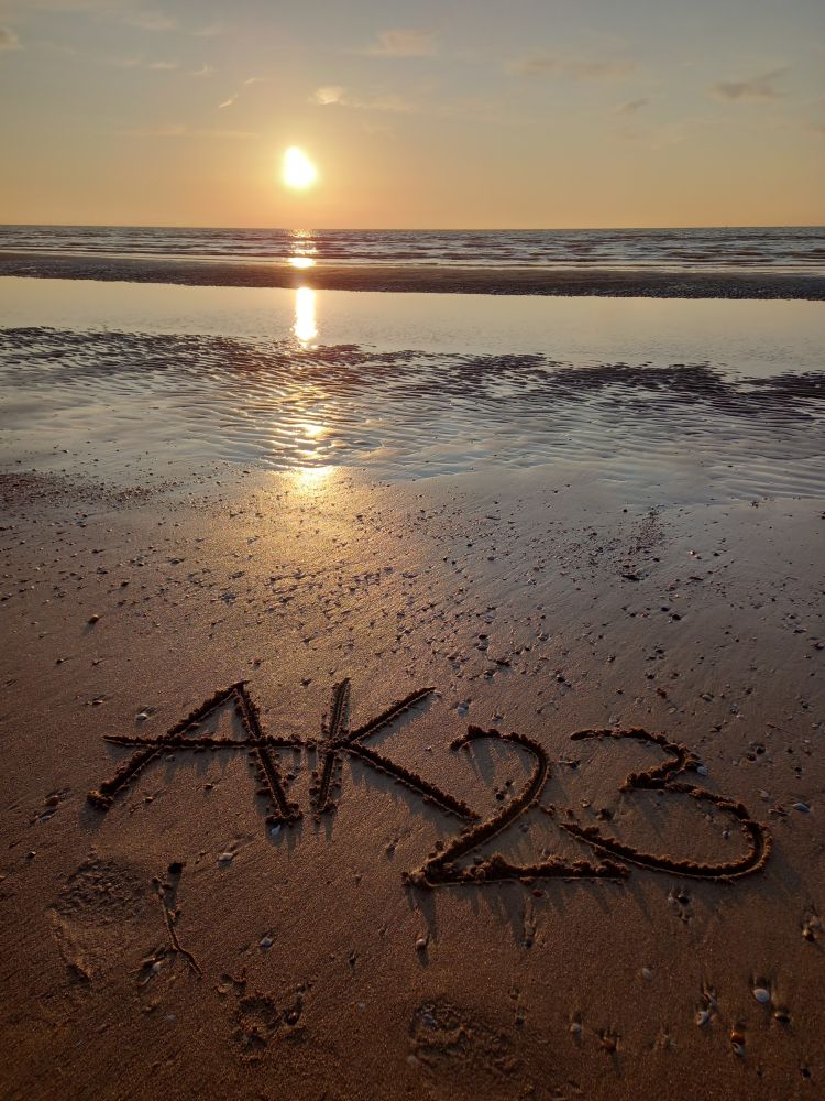 Sonnenuntergang am Strand und AK23 in den Sand geschrieben
