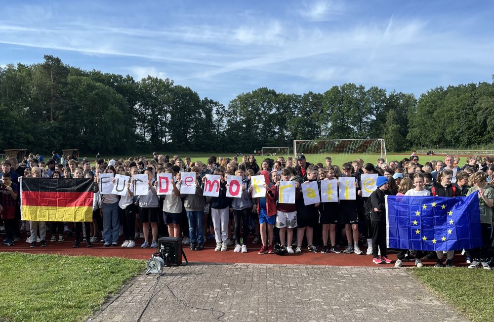 Gruppenfoto der Schülerinnen und Schüler mit der Deutschland- sowie der EU-Flagge und den Buchstaben "Für Demokratie".