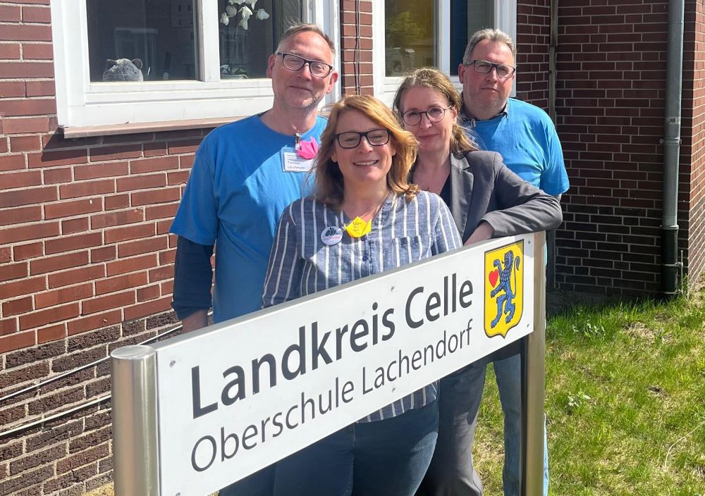 Das Schulleitungsteam vor dem Schild der OBS