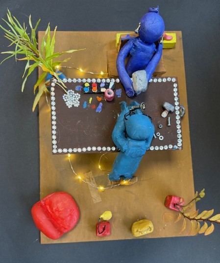 Beleuchtete Knetszene mit zwei Figuren in einer Werkstatt, Skulptur entstanden im Rahmen der Kunstwoche der 8.2